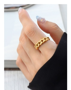 Detailed view of a golden curb chain ring with a polished finish worn on the index finger
