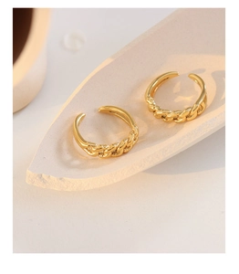 Detail of two gold chain link adjustable rings on a minimalist white stone tray