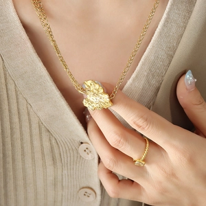 Collar con colgante de hoja dorada y anillo con gema lucidos por modelo sobre punto