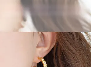 Detail of 18K gold starburst hoop earrings with zircon stones on model's ear