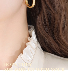 Macro shot of gold hoop earrings with starburst zircon inlay and inner hollow details