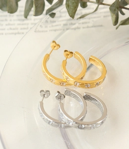 Detailed view of 18K gold star-etched hoop earrings with sparkling zircon inlay