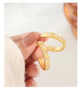 Detail of 18K gold starburst earrings with inlaid zircons worn with a white knit sweater