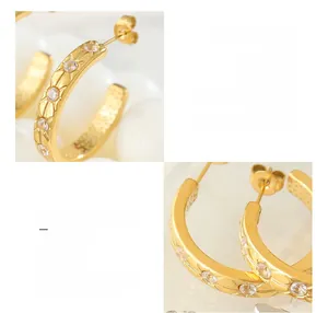 Detailed view of C-shaped titanium steel earrings with starburst zircon inlays