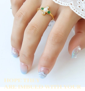 Detail of vintage gold twisted ring featuring baroque pearl and emerald green stones