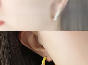 Detailansicht der gelben Emaille C-Ohrringe mit Zirkonia-Inlay am Ohr des Models