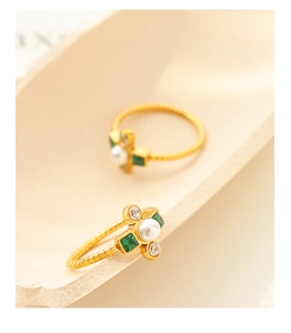 Detailed macro view of baroque pearl rings with emerald stones and gold twisted bands