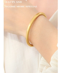 Close-up of a matte gold circular bangle worn on wrist with a minimalist design