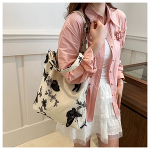 Close-up of butterfly embroidery and lace floral patterns on white canvas tote bag