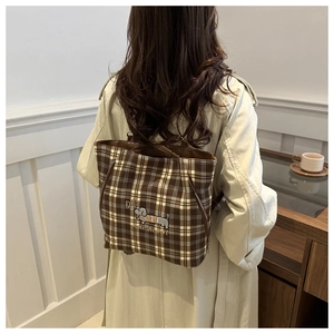 Detail of dachshund embroidery on brown checkered tote bag worn as a backpack