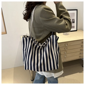 Detailed side view of a large blue and white striped canvas tote bag on shoulder