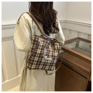 Detail of checkered tote bag featuring dog embroidery and premium brown leather straps