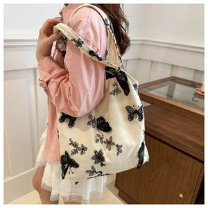 Close-up of black butterfly and floral embroidery on durable off-white canvas tote bag
