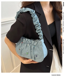 Close-up of light blue pleated denim shoulder bag with colorful gemstone studs