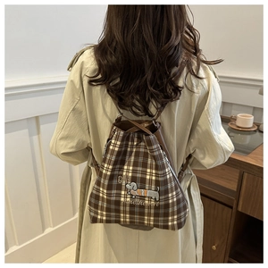 Detailed view of brown plaid tote with dachshund embroidery on a beige trench coat