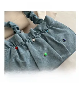 Macro shot of blue denim pleated shoulder bag with colorful beads and cloud handle detail