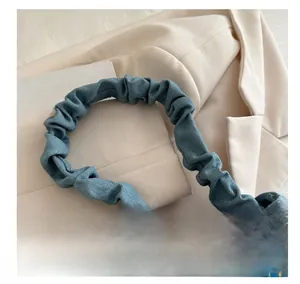 Detail of ruched denim handle on blue shoulder bag with decorative blue beads