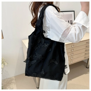 Detail of black lace tote bag featuring 3D butterfly embroidery in a shoulder carry view