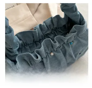 Detailed close-up of denim ruched cloud bag with colorful studs and secure black zipper