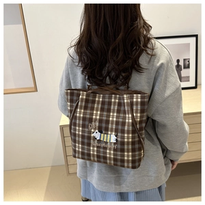 Close-up of brown plaid tote bag featuring a cute cartoon dog embroidery and side zipper