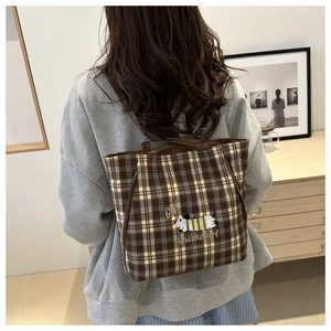 Brown plaid canvas tote bag with dog embroidery shown in a minimalist home setting