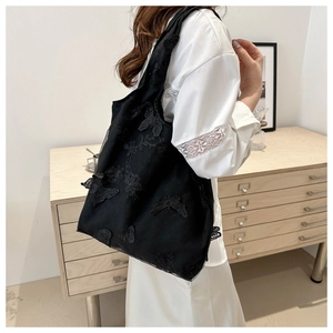 Close-up of black mesh tote bag with 3D butterfly embroidery shown in a lifestyle setting