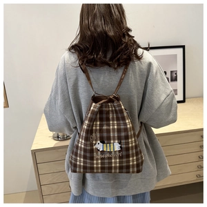 Detailed back view of model wearing a brown checkered bucket backpack with dog embroidery
