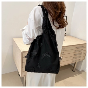 Detail of 3D butterfly embroidery on black mesh tote bag with shoulder straps