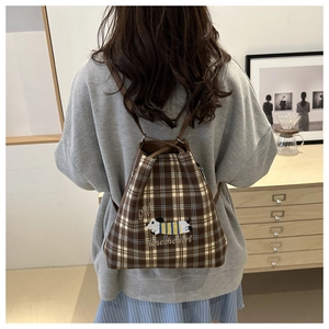 Detailed back view of model wearing the plaid backpack with dog embroidery and leather straps
