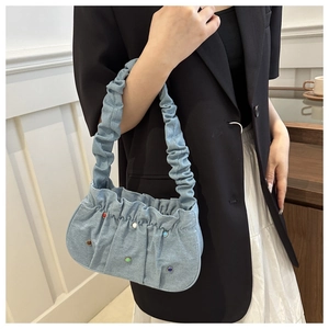 Detail of light blue denim baguette bag with colorful bead accents and a scrunchie handle