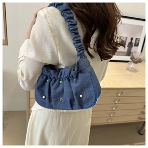 Detail of dark blue denim cloud bag with pleated strap and pearl bead embellishments