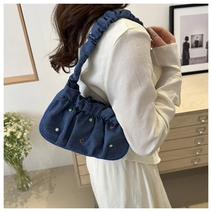 Detail of blue denim pleated shoulder bag with colorful studs and ruched cloud handle