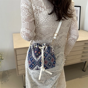 Chic bohemian bucket bag with geometric patterns and white leather straps shown on model