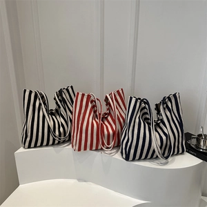 Large striped canvas tote bag in black red and navy colors shown on display steps