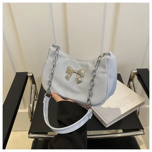 Detail of light blue shoulder bag featuring a silver metal bow and chunky chain strap