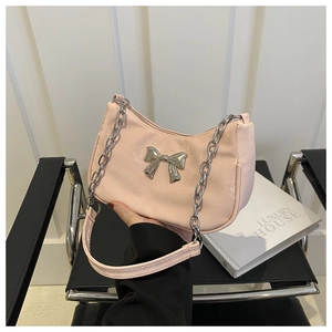 Detailed view of light pink hobo bag featuring a silver bow and metal chain strap