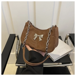 Detail of a brown crescent shoulder bag featuring a silver bow buckle and metal chain