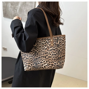 Close-up of leopard print canvas tote bag with gold rivets on brown leather handles