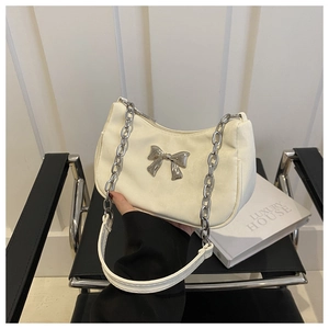 Detail of white crescent hobo bag featuring a metallic bow and silver chain strap