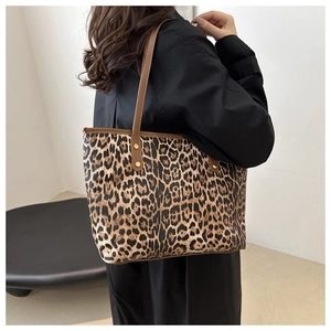 Detailed view of leopard print tote bag with brown straps and rivets shown on model