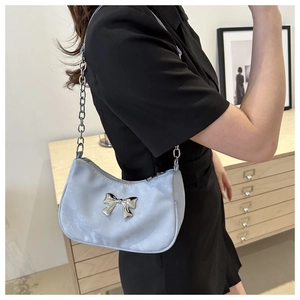Close-up of light blue silk baguette bag with silver bow accent and chain strap