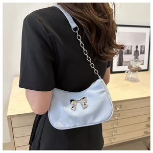 Detail of light blue crescent bag featuring a silver bow and metal chain strap