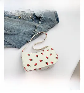 Détail du sac à bandoulière en velours côtelé blanc avec motifs de fraises brodés