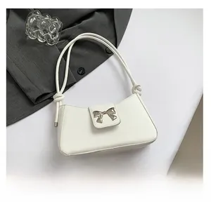 Close-up of white shoulder bag with silver butterfly clasp and knotted handle detail