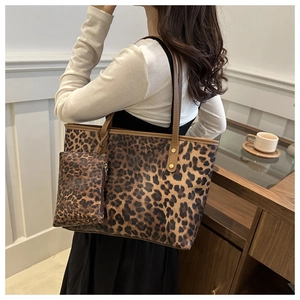 Detail view of leopard print tote bag with small zipper pouch and brown leather straps