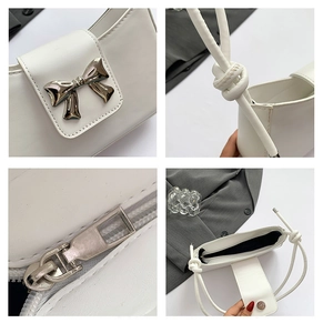 Detailed view of white PU leather shoulder bag featuring silver bow and knotted strap