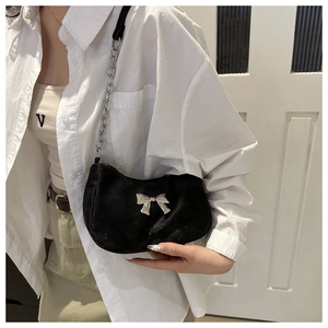 Detail of black velvet underarm bag with silver bow ornament and metal chain strap