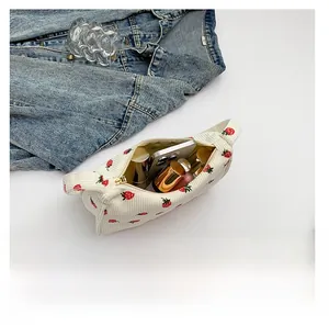 Détail de la capacité intérieure montrant une trousse de maquillage à imprimé fraise