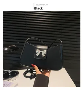 Detailed view of black shoulder bag with silver butterfly metal buckle on a desk