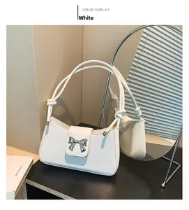 Close-up of white leather shoulder bag with silver bow buckle and knotted handle detail